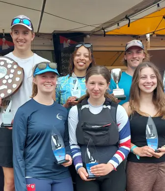 A group of six students smiling whilst holding cups and trophies at the Royal Hospital School Sailing Academy, Ipswich