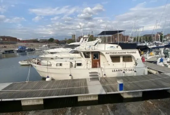Long distance view of the Matthews Marine training cruiser boat moored alongside a marina