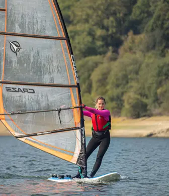A young woman windsurfing on the reservoir at Llandegfedd Watersports, Pontypool, Gwent