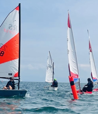 Dinghies with bright orange and white striped sails racing at South Caernarvonshire Yacht Club, Abersoch, Wales