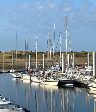 A marina full of yachts set against the hills and blue sky in the background