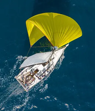 Aerial of a yacht with a large yellow spinnaker sailing on the water at Center of Sailing - Centar Jedrenja, Croatia