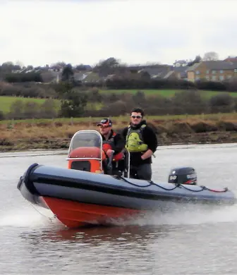 Two men speeding along the water in a rigid inflatable boat (RIB)