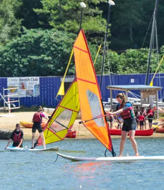 Children learning to windsurf on the water at Rockley Point Sailing Centre, Poole, Dorset