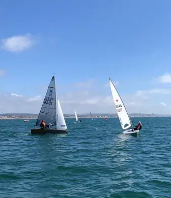 Two dinghies sailing on the water with blue sky in the background