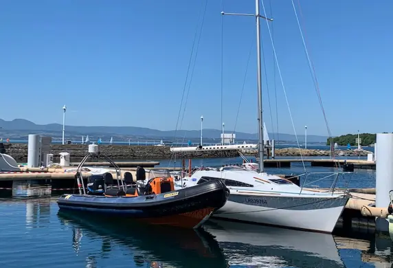 A rib and a yacht moored alongside each other in a marina
