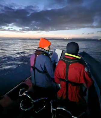 Two people navigating on a rigid inflatable boat (RIB) in the dark with Ocean Sports Tuition, Southampton