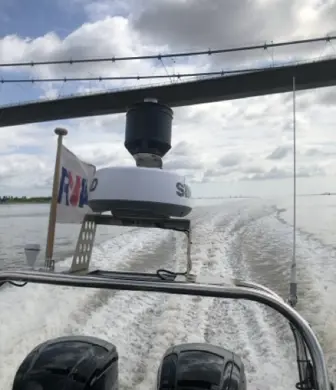 The back of a double engine rigid inflatable boat (RIB flying an RYA flag speeding across the water