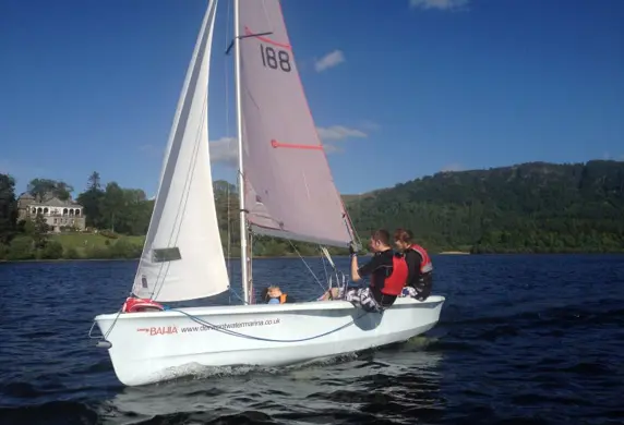 Two young people on a small sail boat sailing on the Derwent Water in the Lake District on a sunny day