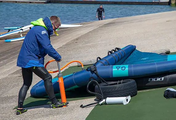A man inflating a wing foil on the shore at Carsington Sports and Leisure, Ashbourne, Derbyshire