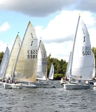 A large group of small sail boats at the start of a race