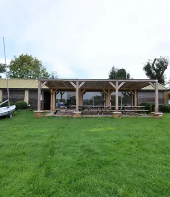 The front of a club house with yachts on trolleys on the grass on either side