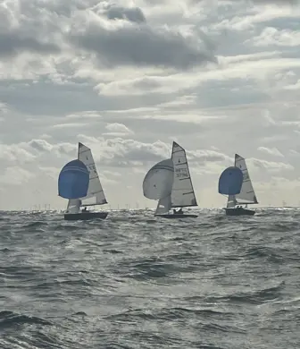 Three yachts sailing with their spinnakers up on a grey cloudy day