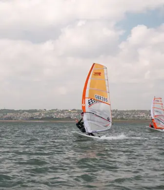 Two windsurfers on the water on a cloudy day at the Andrew Simpson Watersports Centre, Portsmouth