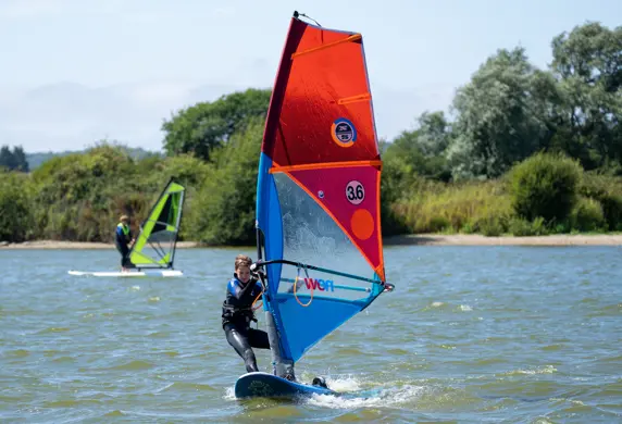 A young person windsurfing on the water