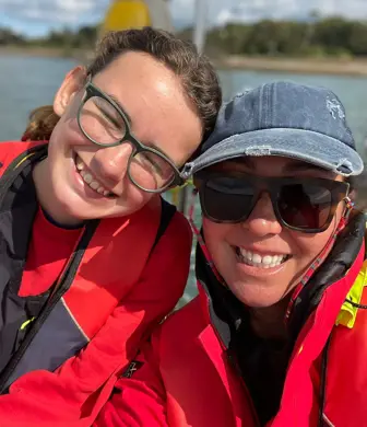 A close up shot of two ladies smiling, wearing wet weather gear after a good day on the water