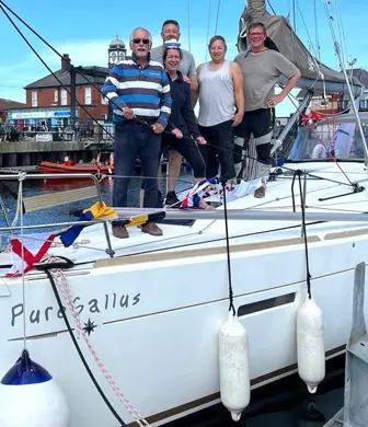 The crew of a tall ship standing on the deck while the boat is moored in the marina