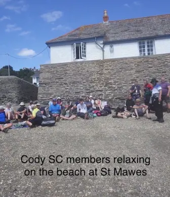 A group of members from Cody Sailing Club relaxing on the beach at St Mawes, Cornwall