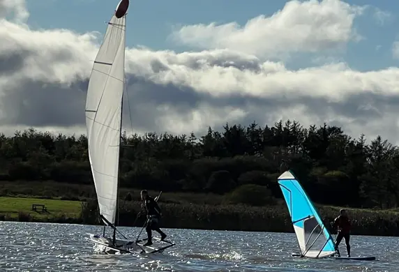 A dinghy and a windsurfer on the water