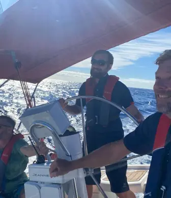 Three people enjoying a day sailing on a sunny day