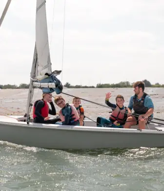 A family enjoying sailing a small sail boat at the Andrew Simpson Watersports Centre, Portsmouth