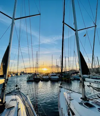 The harbour at sunset as seen from onboard a yacht through all the masts