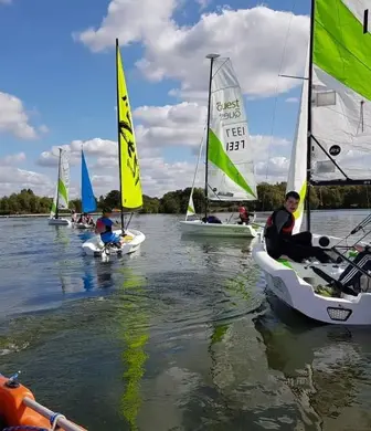 A group of Picos with different coloured sails sailing on calm water