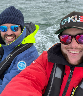 Two men wearing wet gear and reflective sunglasses enjoying a day on the water with Ocean Sports Tuition, Southampton