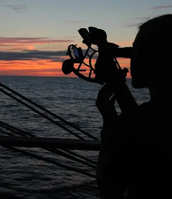 A lady on a yacht at dusk using a sextant