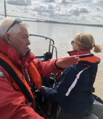 A lady driving a rigid inflatable boat (RIB) whilst receiving training from an instructor