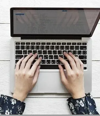 Aerial shot of a pair of ladies hands positioned over the keyboard of a laptop