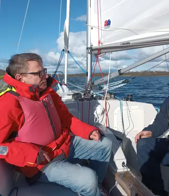 Two men smiling on a yacht sailing on the Llandegfedd Reservoir at Llandegfedd Watersports, Pontypool, Gwent