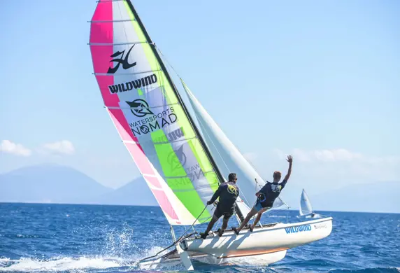 Two men hiking out of a Hobie cat catamaran on a beautiful sunny day at Watersports Nomad, Vassiliki, Greece