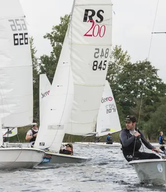 A group of RS 200s racing on the water on a grey day