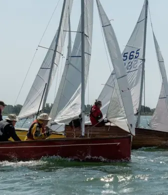 A group of 3 yachts with two sails up preparing to round a mark during a race