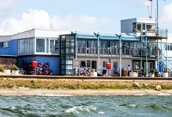 A windsurfer passing the club house at the Queen Mary Sailing Club, Ashford