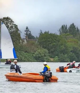 An on the water teaching session with two small dinghies sailing, being supported by safety ribs